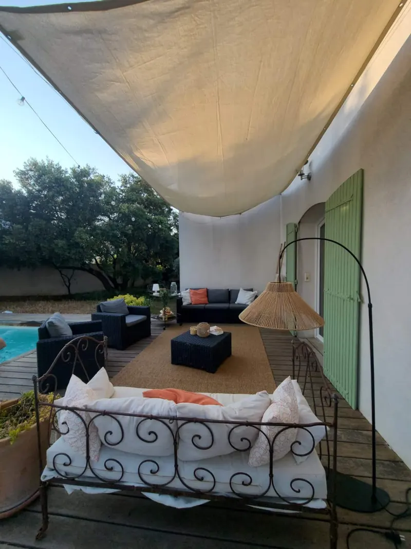 Salon extérieur sous voile d'ombrage au bord de la piscine